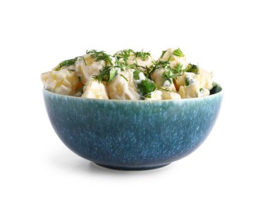 Beyaz arka planda yeşil salatalı bir kase lezzetli patates salatası.