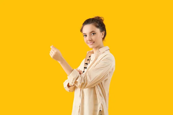 Young Woman Rolling Her Sleeve Yellow Background — Stockfoto