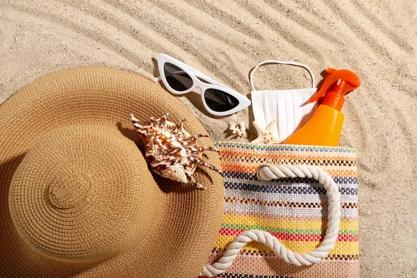 stock image Bag with bottle of sunscreen cream, medical mask, beach accessories and seashells on sand. Melanoma concept