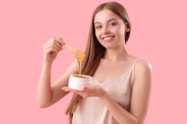 Pretty young woman with sugaring paste on pink background