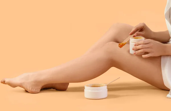 Młoda Kobieta Nakładająca Pastę Cukrową Nogi Beżowe Tło — Zdjęcie stockowe