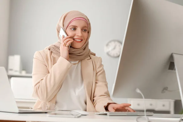 オフィスのテーブルで携帯電話で話すイスラム教徒の女性プログラマー — ストック写真