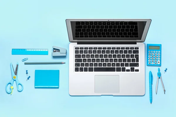 Composition with laptop and stationery on blue background