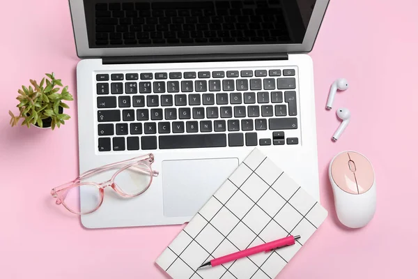 Composition with laptop, eyeglasses and notepad on pink background