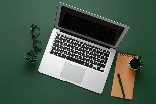 Composition with laptop, plants and notepad on green background