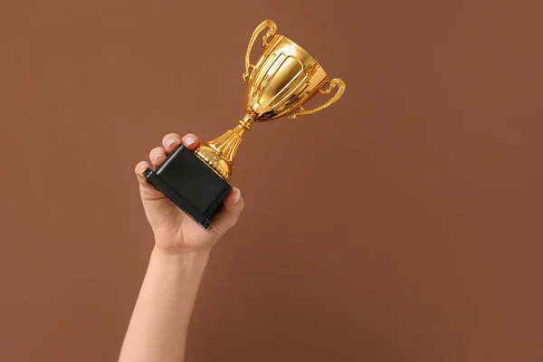 Woman with gold cup on brown background