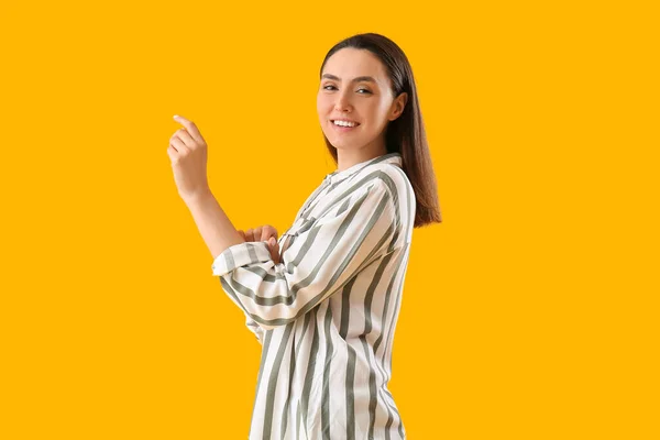 Mooie Jonge Vrouw Rollen Omhoog Haar Mouw Gele Achtergrond — Stockfoto