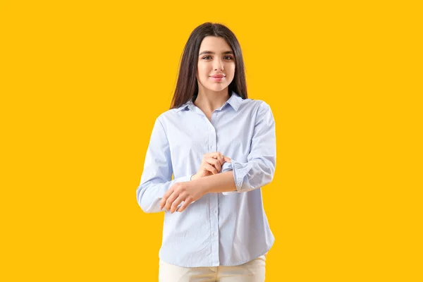 Piękna Młoda Kobieta Podwijająca Rękaw Żółtym Tle — Zdjęcie stockowe