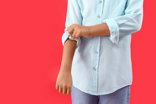 Little boy rolling up his sleeve on red background