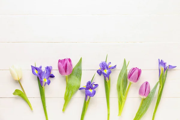 stock image Tulips with iris flowers on white wooden background