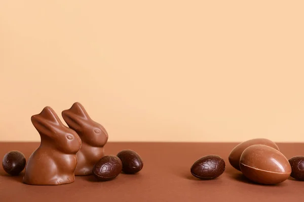 Chocolade Paaseieren Konijntjes Bruine Tafel Tegen Beige Ondergrond — Stockfoto