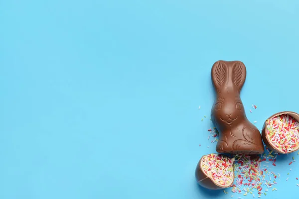 黒チョコレートイースターエッグにスプリンクルとウサギの青い背景 — ストック写真