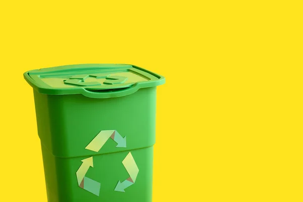 黄色の背景にゴミのための緑のコンテナ リサイクルコンセプト — ストック写真