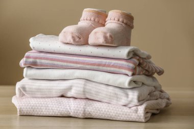 Bebek kıyafetleri ve çorapları renkli duvarın yanındaki ahşap masada, yakın plan.