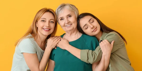 幸せな成熟した女性の肖像とともに彼女の娘と母親上の黄色の背景 — ストック写真