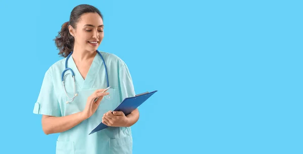 stock image Female medical assistant with clipboard on light blue background with space for text