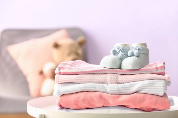 婴儿衣服和袜子堆在房间的桌子上 特写镜头 — 图库照片