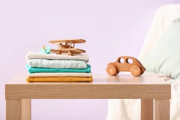 Stapelweise Babykleidung Schnuller Und Holzspielzeug Auf Dem Tisch Vor Der — Stockfoto