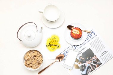 Çay seti, mısır gevreği, kek, kart ve cep telefonlu kompozisyon