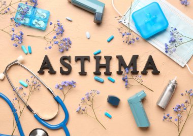 Astım spreyi, hap, steteskop ve bej arkaplanda çiçekler olan ASTHMA kelimesi