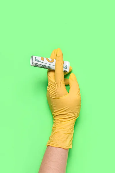 Woman in medical glove with money on green background