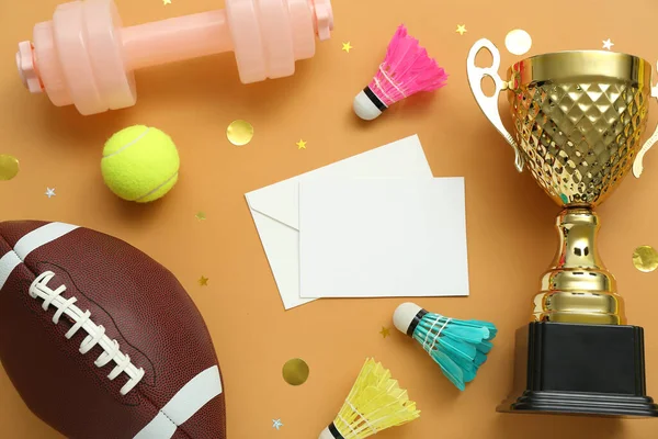 Blank card with gold cup, sports equipment and confetti on orange background