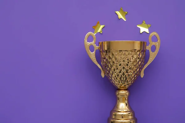 Gold cup with stars on purple background, closeup