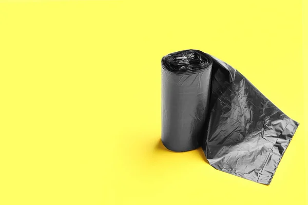 黄色の背景にゴミ袋の黒いロール — ストック写真