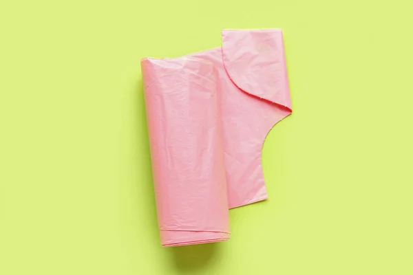 緑の背景にゴミ袋のピンクのロール — ストック写真