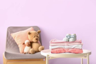 Bebek kıyafetleri ve çoraplar renkli duvara karşı.