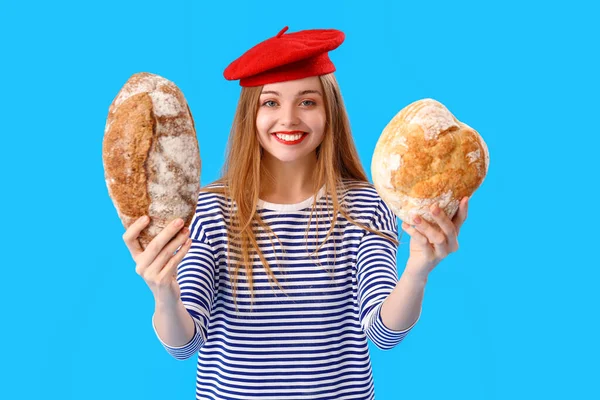 Młoda Kobieta Berecie Bochenkami Świeżego Chleba Niebieskim Tle — Zdjęcie stockowe