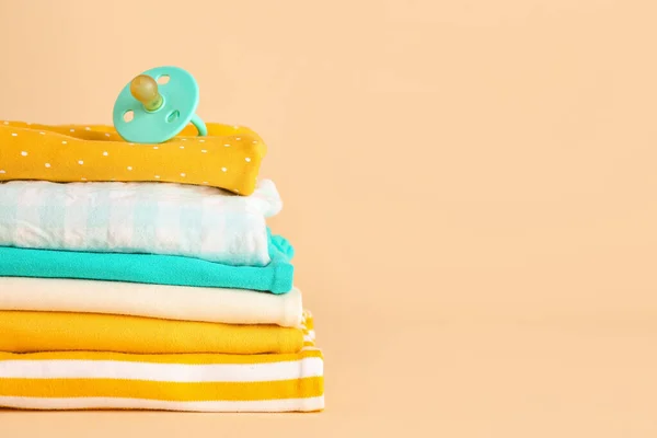 Stapel Verschiedener Babykleidung Und Schnuller Auf Farbigem Hintergrund — Stockfoto