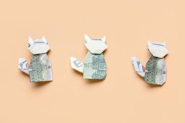 Origami kedileri bej arka planda dolar banknotlarından yapılmıştır.