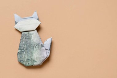 Origami kedisi bej arka planda dolar banknotlarından yapılmıştır.