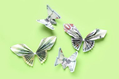 Yeşil arka planda dolar banknotlarından yapılmış Origami kelebekleri