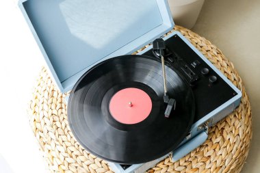 Pouf 'ta vinil diski olan kayıt çalar, yakın plan.