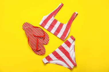 Sarı arka planda mayosu olan parmak arası terlikler.