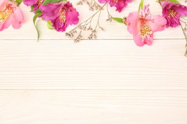 Beyaz ahşap arka planda çingene çiçekli pembe alstromerya.