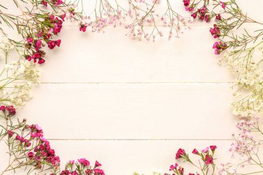 Beyaz ahşap arka planda çingene çiçeklerinden yapılmış çerçeve