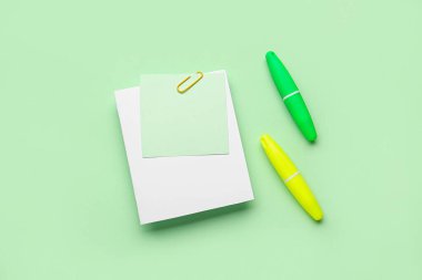 Kağıt raptiyeli yapışkan notlar ve yeşil arkaplanda işaretleyiciler