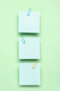 Yeşil arkaplanda ataçları olan yapışkan notlar