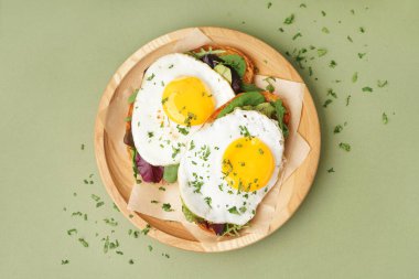 Yeşil arka planda kızarmış yumurtalı lezzetli sandviçler.