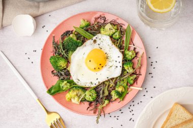 Lezzetli kızarmış yumurta ve gri arka planda salata.