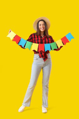 Sarı arka planda bayrakları olan genç bir kadın. Festa Junina (Haziran Festivali) kutlaması