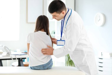 Doktor klinikteki küçük kızın duruşunu kontrol ediyor.