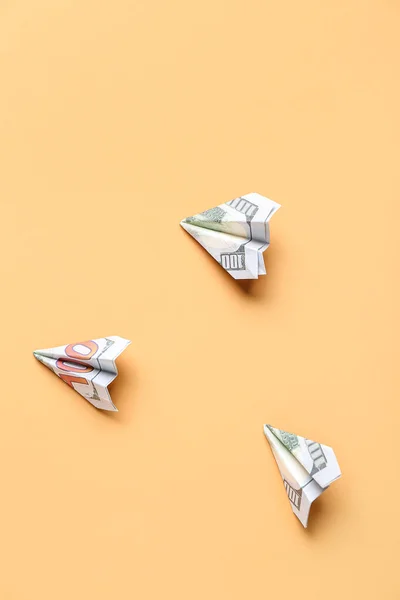Origami planes made of dollar banknotes on beige background