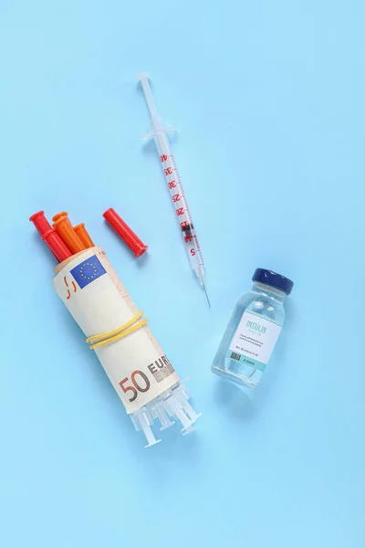 Insulin with syringes and money on blue background. Expensive medicine concept