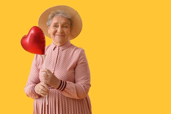 Mulher Sênior Com Balão Forma Coração Fundo Amarelo — Fotografia de Stock