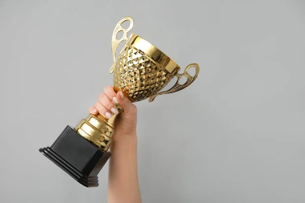 Woman with gold cup on grey background