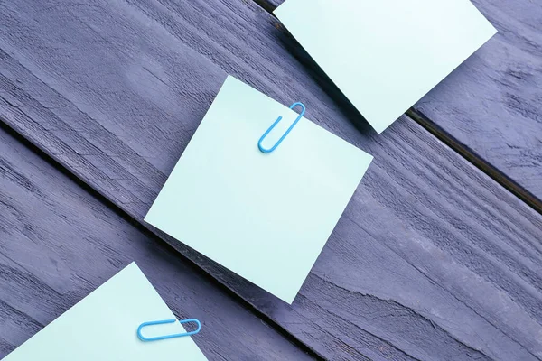 Sticky notes with paper clips on blue wooden background